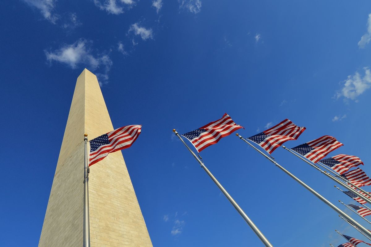 Washington Monument with waving United States National Flags on flagpoles - Washington DC United States